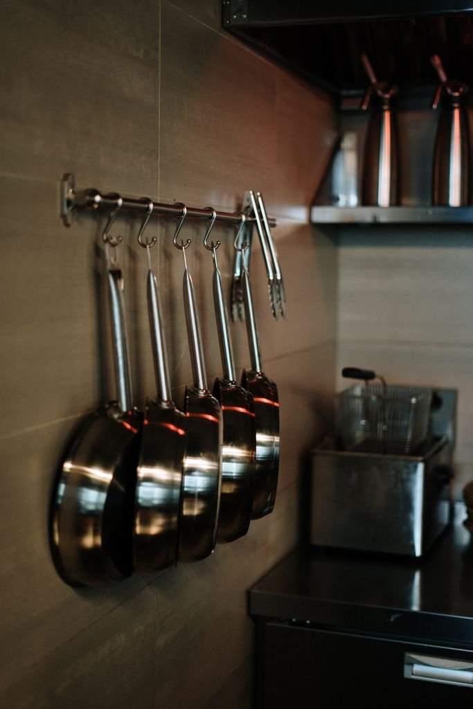 PFAS-free cookware brands — stainless steel pans hanging in a modern kitchen