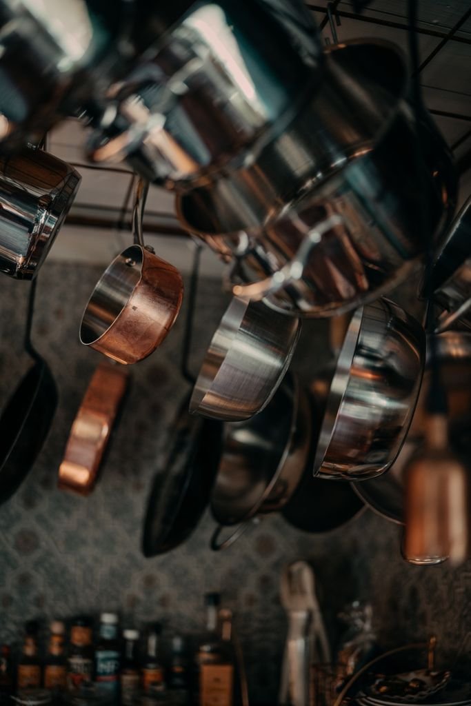 Stainless steel and copper cookware hanging in a kitchen, representing verified, well-maintained cookware